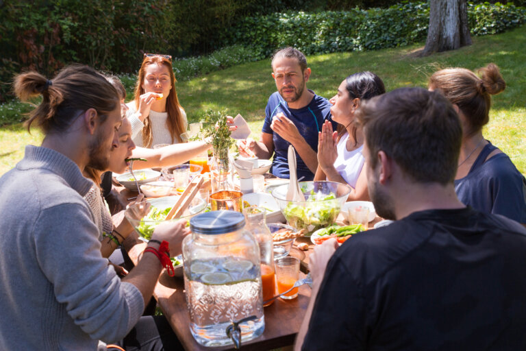 Portrait of serious young people having brunch outdoors. Friends or family eating at table outdoors. Outdoor party or brunch concept